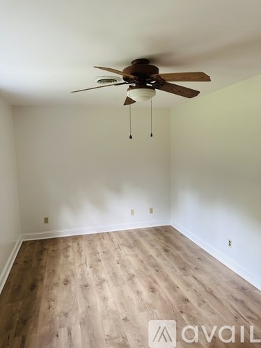 A room with a ceiling fan and wooden flooring.