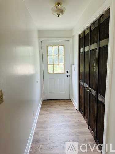 A hallway with a white door and a wooden door on the right.