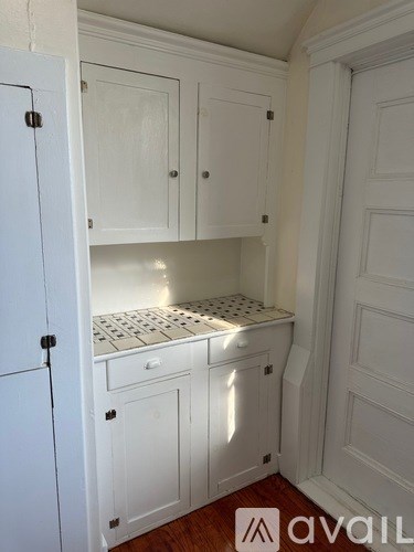 A kitchen with white cabinets and a checkered countertop.