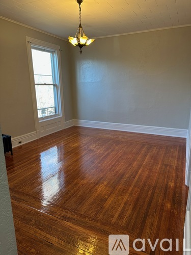 A room with wooden flooring and a chandelier.