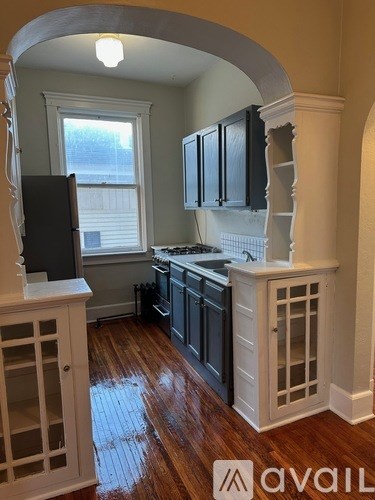 A kitchen with black cabinets and a wooden floor.
