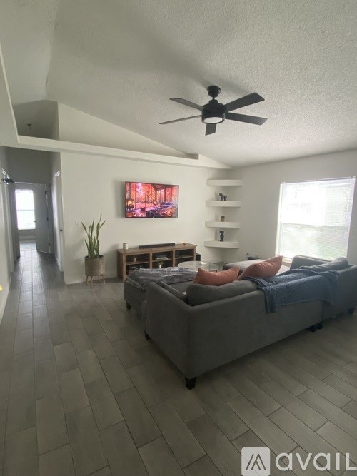 A living room with a grey couch and a ceiling fan.