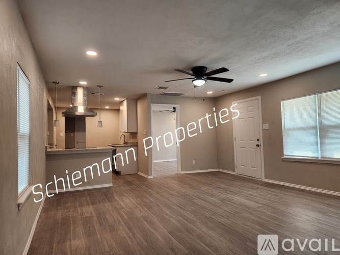 A spacious room with a kitchen area and a ceiling fan.