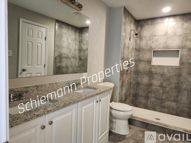 A bathroom with a marble countertop and a walk-in shower.