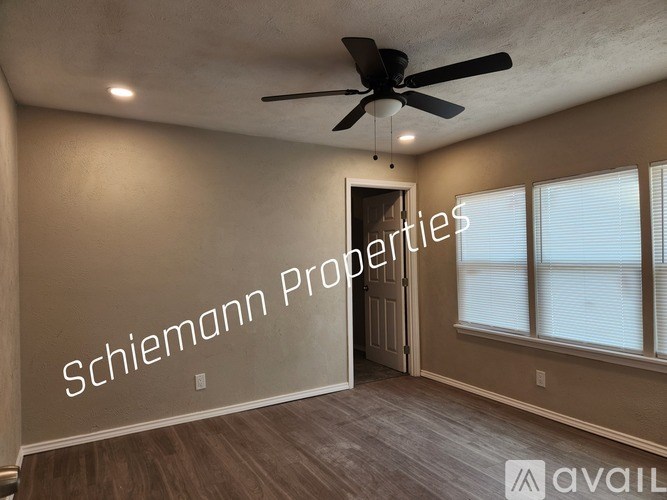 A room with a ceiling fan and a wall that says "Schiemann Properties".