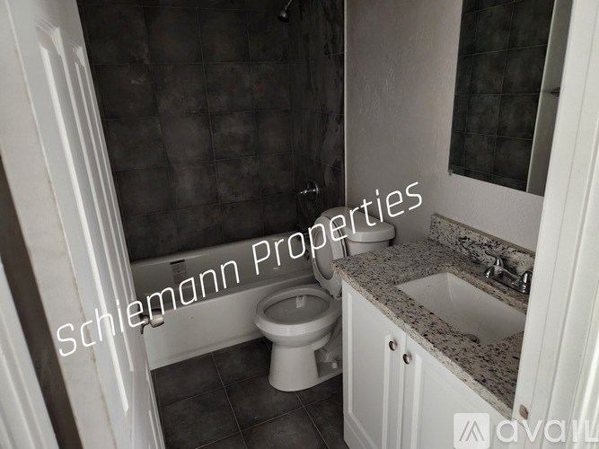 A bathroom with a toilet, sink, and tiled walls.