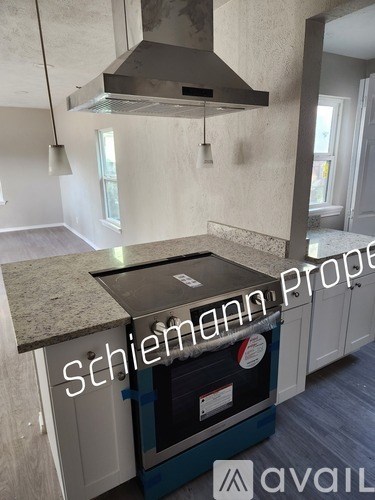 A kitchen with a granite countertop and a stainless steel hood.