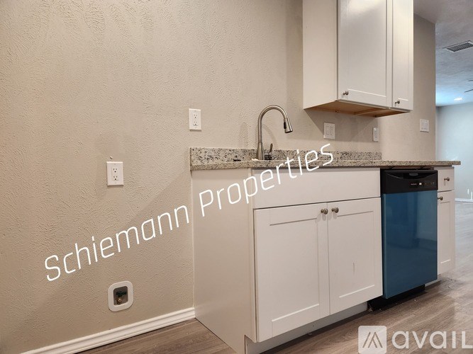 A kitchen with a blue trash can and white cabinets.