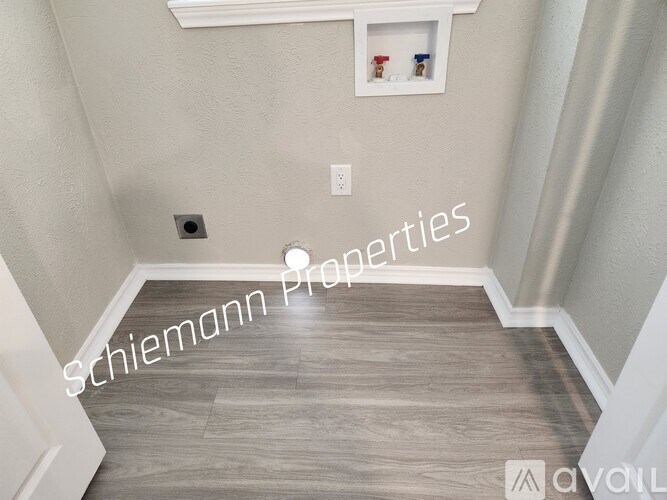 A hallway with a wood floor and a white wall.