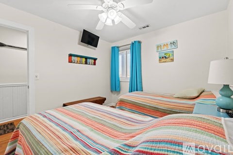 A bedroom with two beds and a ceiling fan.