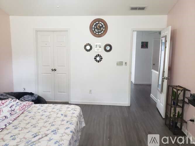 A bedroom with a bed, dresser, and a wall clock.