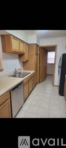 A kitchen with wooden cabinets and a black refrigerator.