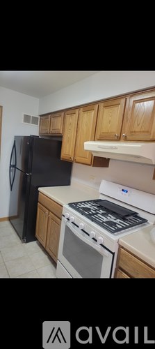 A kitchen with wooden cabinets and a black refrigerator.