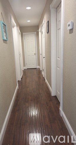 A long hallway with wood floors and white walls.