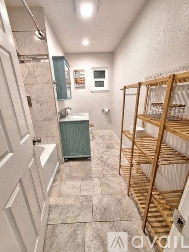A bathroom with a white door, a green cabinet, a white sink, and a wooden shelf.