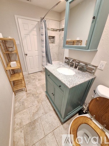 A bathroom with a sink, toilet, and a mirror.