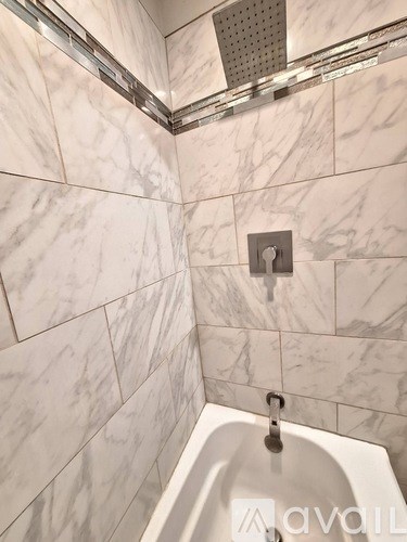 A white bathroom with a marble tile wall and a white sink.