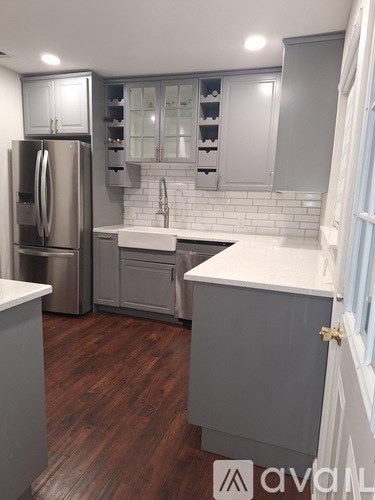 A kitchen with a refrigerator, sink, and cabinets.