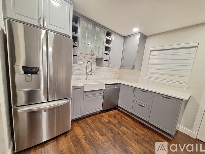 A kitchen with a stainless steel refrigerator and wooden floors.