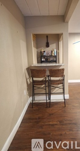 A small bar area with two stools and a shelf of bottles.