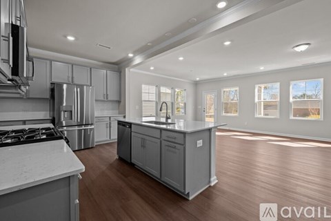 A modern kitchen with stainless steel appliances and wooden flooring.