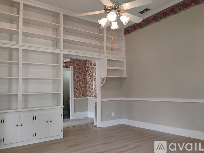A room with a ceiling fan and built-in shelves.