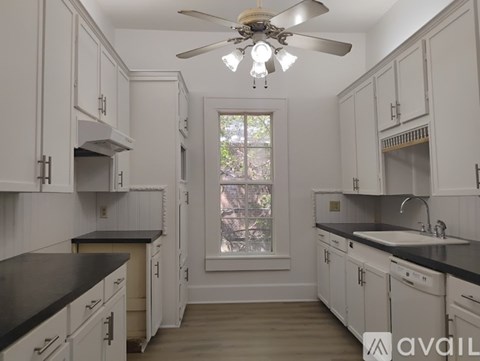 A kitchen with white cabinets and a ceiling fan.