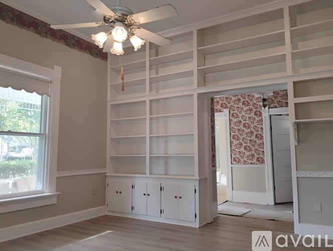 A room with a ceiling fan and built-in shelves.