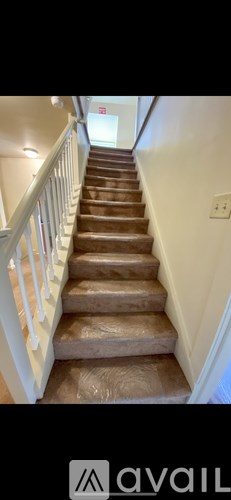A staircase with a white railing and brown steps.