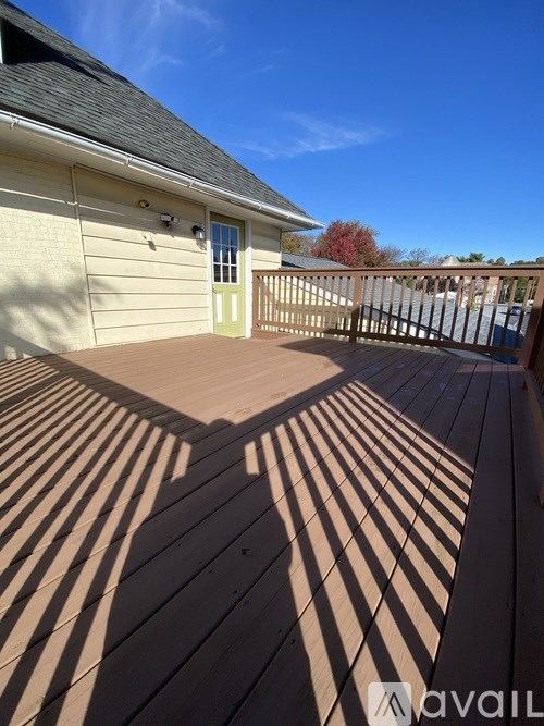 A wooden deck with a house and a fence in the background.