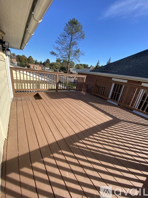 A wooden deck with a white railing and a tree in the background.
