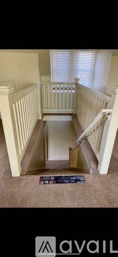 A stairway with a carpeted floor and a black box on the floor.