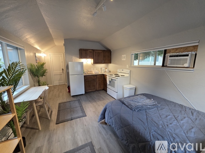 A bedroom with a bed, a table, and a refrigerator.