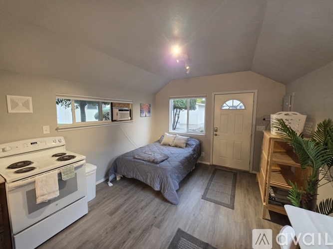 A small bedroom with a bed, dresser, and a stove.