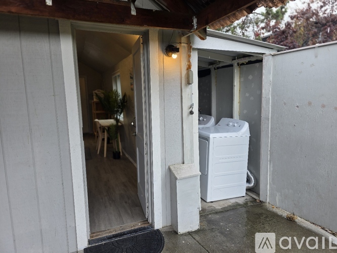 A small white portable building with a door open to a patio.