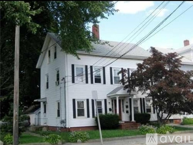 A white house with a black roof and a chimney.