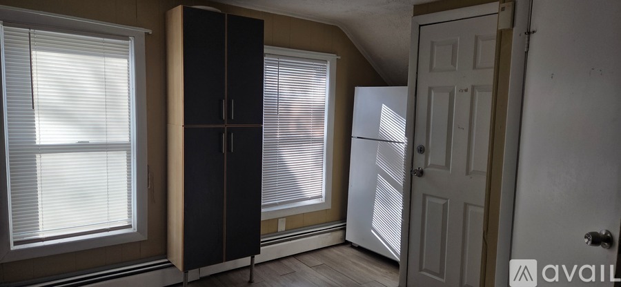 A room with a black cabinet, a white door, and a window with blinds.