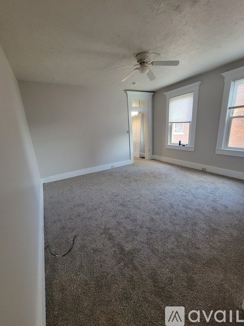 A room with a carpeted floor and a ceiling fan.