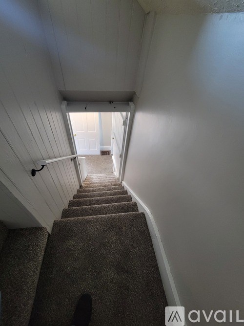 A staircase with a carpeted runner and white walls.