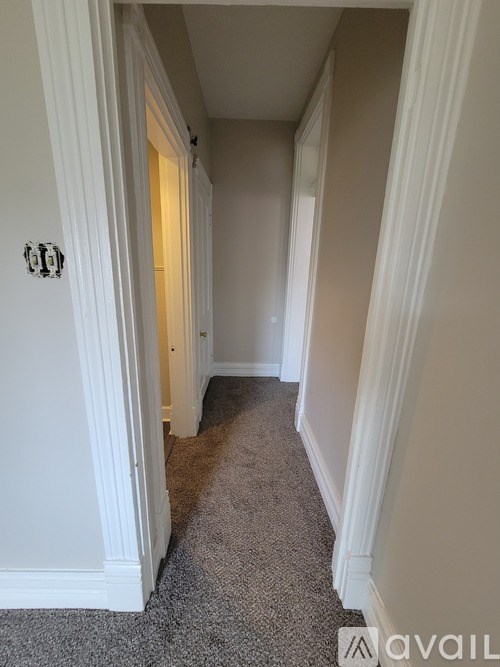 A hallway with a carpeted floor and white walls.