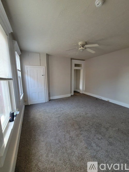A room with a carpeted floor and a ceiling fan.