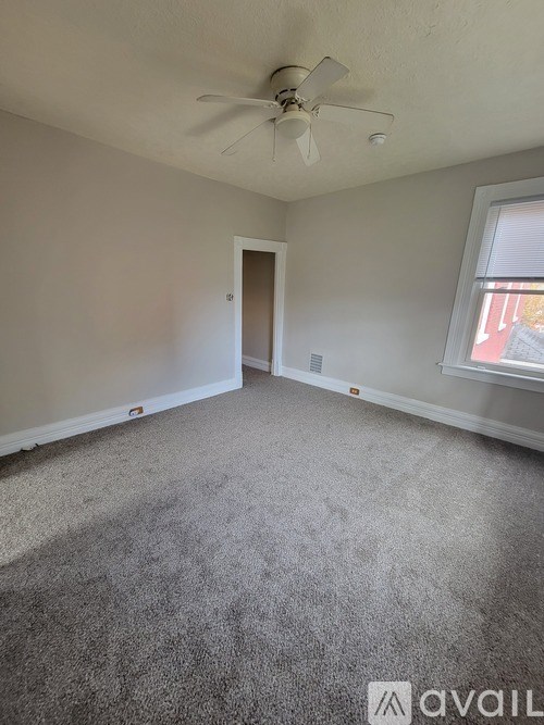 A room with a carpeted floor and a ceiling fan.