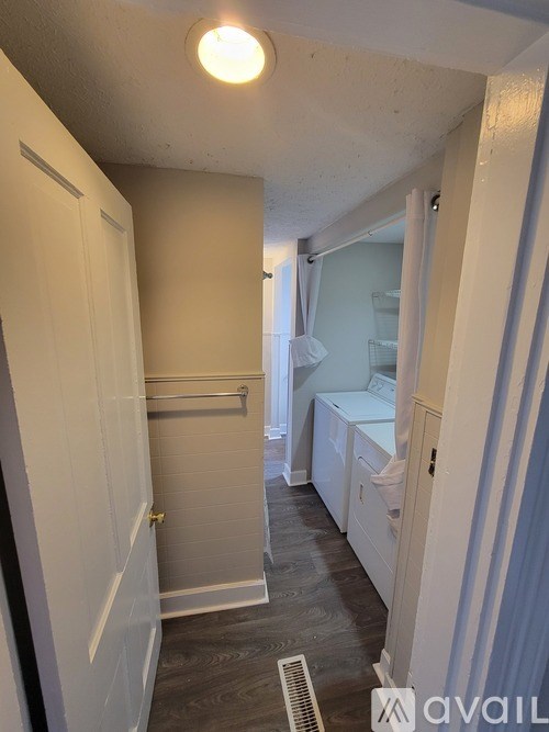 A small, empty room with a white door and a window with white curtains.