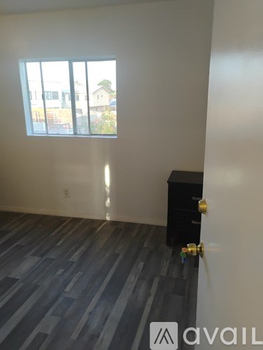 A room with a black cabinet and a window showing a view of a building outside.