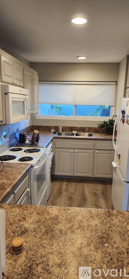 A kitchen with granite countertops and white appliances.