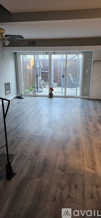 A room with a ceiling fan and sliding glass doors.