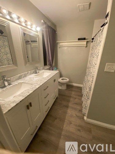 A bathroom with a sink, mirror, toilet, and a lighted mirror.