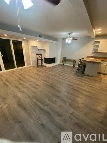 A spacious room with wooden flooring and a ceiling fan.