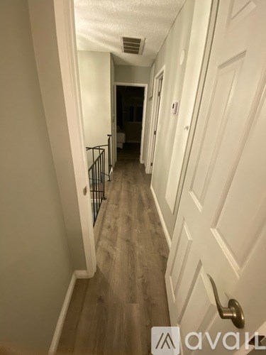 A hallway with a white door and a black railing.