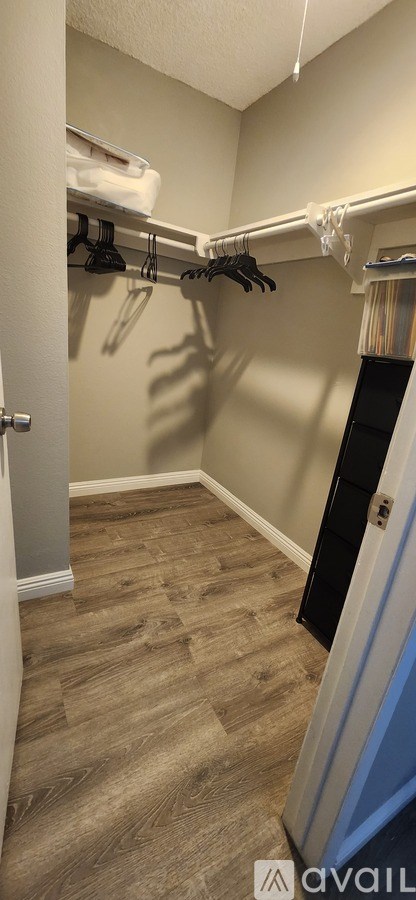 A room with a wooden floor and clothes hanging on a rail.